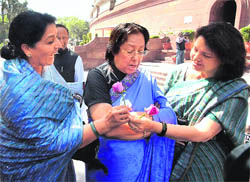 Women MPs Maya Singh, Najma Heptulla (C) and Renuka Chowdary (L) exchange flowers on International Womens Day at Parliament House in New Delhi on Friday. 
