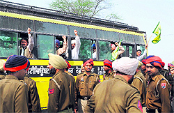 Arrested farmers raise slogans against the state government while being taken to a police station