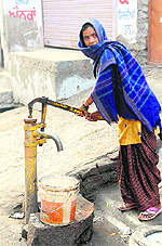 A woman draws water from a hand pump installed in the city
