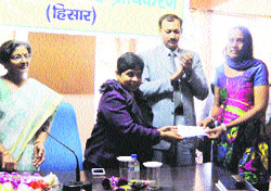 Neelam Pradeep Kasni, Commissioner of Hisar division, gives a prize to a representative of a mahila mandal at Hisar.