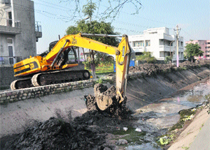 An excavator at work near Ranbir Canal for desilting the canal in Jammu on Monday.