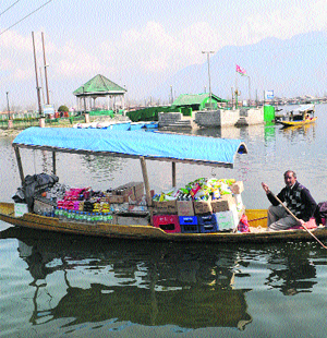 A boatman rows a shikara full of food items on the Dal Lake in Srinagar on Monday.
