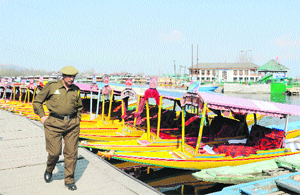 A policeman walks past shikaras at the Dal Lake in Srinagar on Monday.