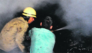 Firemen dousing the flames at the Guru Nanak Avenue on Majitha road in Amritsar on Wednesday. 