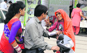 A couple on a two-wheeler is accosted by a beggar. Beggars have become ubiquitous at traffic lights in the city, much to the annoyance of motorists.