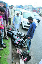 A motorcyclist looks at his two-wheeler, damaged after another motorcyclist reportedly crossed the road from the wrong side in Jammu on Thursday.
