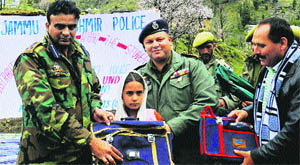 JK Police officers distribute school material among poor children at Rajouri on Thursday. 