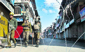 Policemen patrol a street in Srinagar during curfew on Friday. 