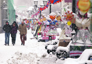 People walk past traditional Maslenitsa spring festival decorations during a snowstorm in Moscow on Friday