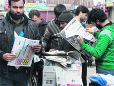 People buy newspapers in Srinagar on Saturday. 