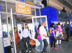 Commuters enter the railway station from an exit point.