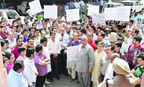 Members of the Mahavir Mandir Trust and shopkeepers of Gur Mandi protest outside the MC's Zone A office in Ludhiana on Monday