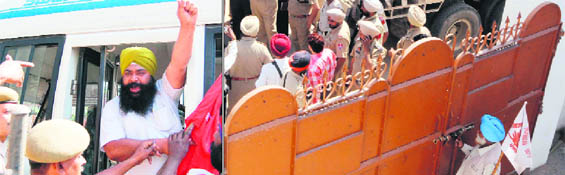 a farmer activist locks the gate of a gurdwara from inside in Piddi village of Tarn Taran; a protester being arrested in Amritsar.