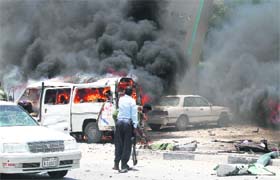 Policemen try to remove remains of their colleagues killed in an explosion near the presidential palace in Somali capital Mogadishu on Monday