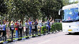 Cricket fans wave at members of the Indian team as they leave for the airport in a bus on Tuesday