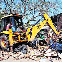 A JCB machine pulls down illegal juggis in Sector 26, Chandigarh, on Tuesday