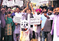 Whoelsale traders of electric and electronic goods, accompanied by members of the Dynamic Group of Congress councillors, burn an effigy of the SAD-BJP government against the imposition of property tax in Jalandhar on Tuesday.