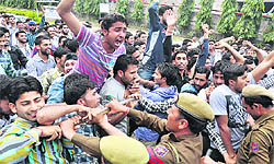 Policemen try to control activists of the All Jammu and Kashmir National Youth Corps during a protest in Jammu on Wednesday
