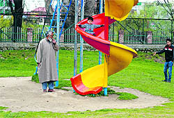 A boy enjoys a ride as an elderly man looks on at a park in Srinagar on Wednesday