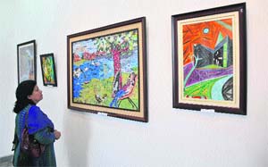 A visitor takes a look at a painting during the 48th state art exhibition at Kala Kendra in Jammu on Thursday. 