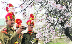 BSF soldiers stand behind a blossoming almond tree in Srinagar on Friday. 