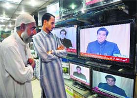 People listening to Pakistan Prime Minister Raja Pervez Ashraf addressing the nation on March 16, at an electronics shop in Islamabad