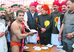 Chief Minister Virbhadra Singh presents the Best Wrestler of Nalwaadi title to Johanny Chaudhary of Sundernagar in Bilaspur on Saturday.