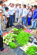An MC official warns a shopkeeper, who had allowed a vegetable vendor to set up a phari in front of his shop in the Jawahar Nagar Camp area, Ludhiana, on Saturday.