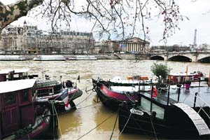Waters of the Seine flow out of its banks across from the National Assembly and the Eiffel Tower