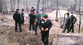 Thai security personnel inspect the site of fire at the Ban Mae Surin refugee camp on Saturday.