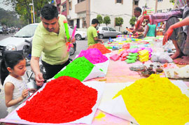 A girl takes a look at Holi colours at a roadside stall.
