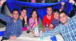 Punjabi writer Shamsher Sandhu and members of the audience take shelter from rain at a music award night in Jalandhar on Saturday