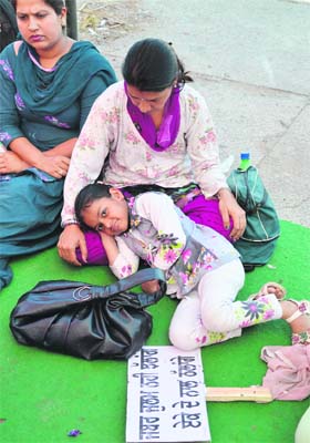 A child who accompanied her mother rests on her lap in Ludhiana on Sunday