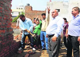 A boundary wall of a plot, which has come up on park land, being demolished in the Joshi Nagar area of Haibowal on Sunday