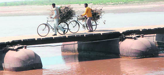 Villagers cross a makeshift pontoon bridge over the Ravi, which is removed every year ahead of the monsoon, near Dharamkot village in Amritsar.