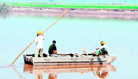 Farmers cross the river in a boat.