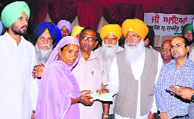 Rajya Sabha member Sukhdev Singh Dhindsa hands over a cheque of Rs 1 lakh to a family member of a deceased farmer in Sangrur on Sunday.