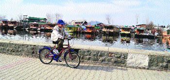 A cyclist rides on the banks of the Dal Lake in Srinagar on Monday. 