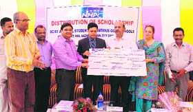Sanjeev Verma, Transport Commissioner (second from left) distributes scholarships at Government Higher Secondary School, Bazar Qasaban, City Chowk in Jammu on Monday.