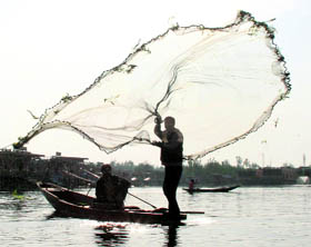 A fisherman casts his net on the Dal Lake in Srinagar on Monday.