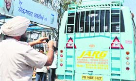 A traffic police official clicks a photograph of a private bus having a black film in Ludhiana on Tuesday