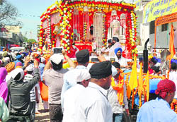 Devotees take pictures of the palki sahib.