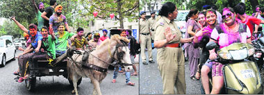 (Left) Holi revellers take a cart ride; and a policewoman stops girls at a checkpoint at Sector 10 in Chandigarh on Wednesday. 