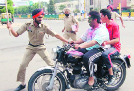 Flouting norms: A policeman stops bikers without helmets in Mohali.