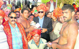 Minister for Food Civil Supplies, Transport and Technical Education GS Bali distributes prizes during a village fair at Nagrota Bagwan on Wednesday.