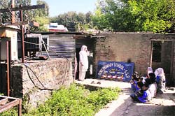 Students of a primary school attend their classes near an electrict transformer at Bijbehara. A Tribune photograph