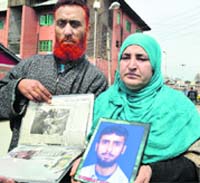 Family members show the photograph of Showkat Ahmad of Lawaypora in Srinagar on Thursday. Tribune Photo: Amin War