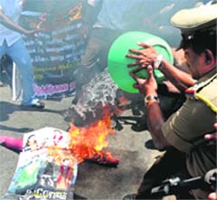 A policeman pours water over a burning effigy during a protest against Sri Lankan war crimes, in Chennai on Wednesday.  PTI
