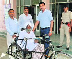 Deputy Commissioner Saket Kumar gives a tricycle to Satpal Singh at Fatehabad on Friday.