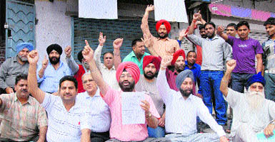 Shopkeepers sit on a dharna in protest against the imposition of property tax in Jalanahar on Friday. 